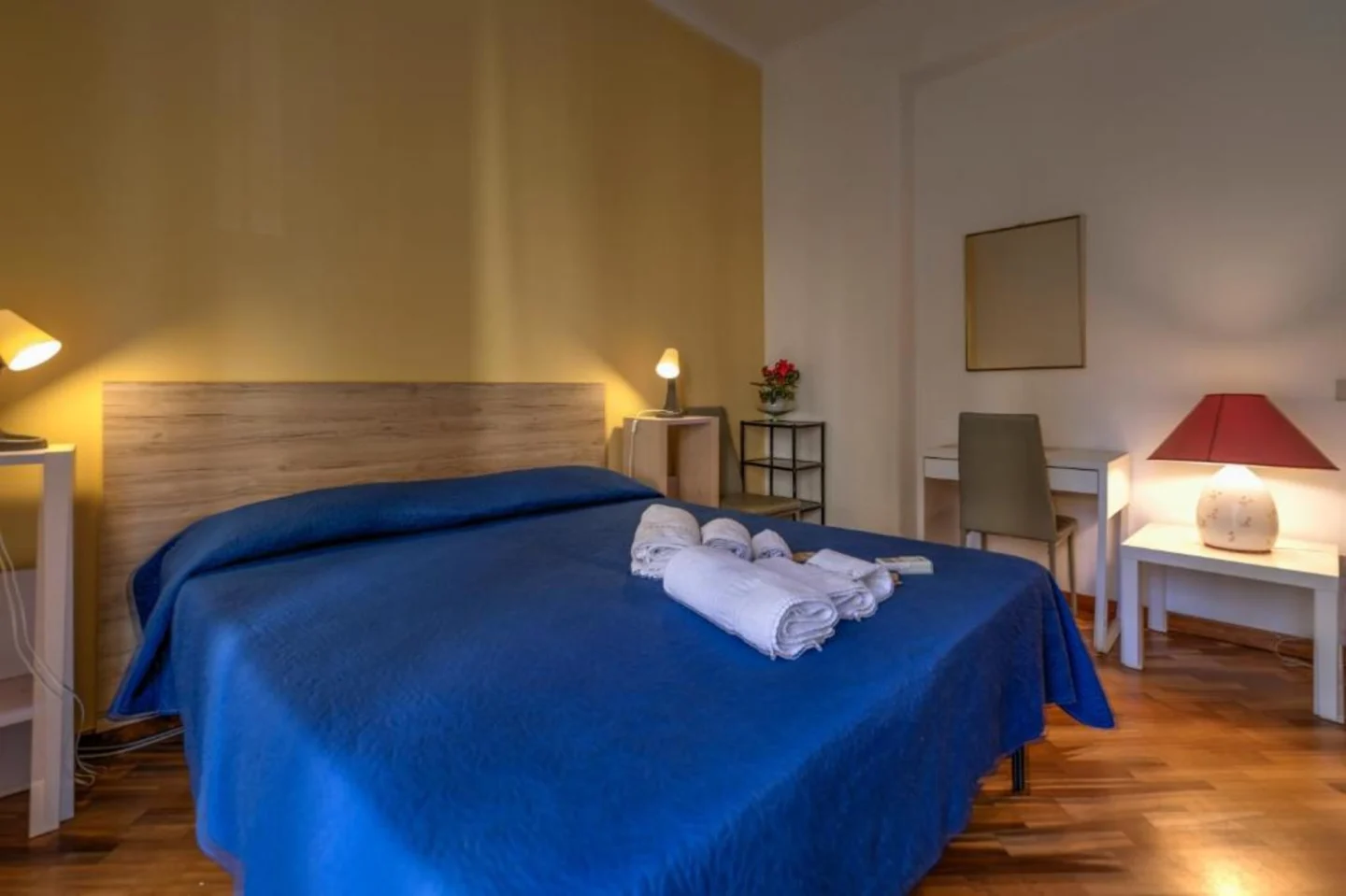 Letto matrimoniale con parete gialla e lampade