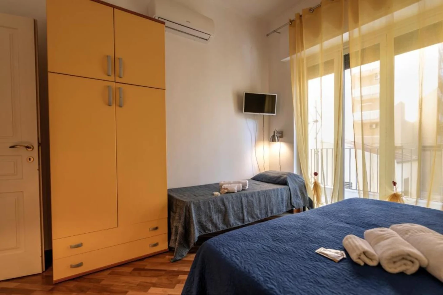 Camera tripla con armadio giallo e letto singolo