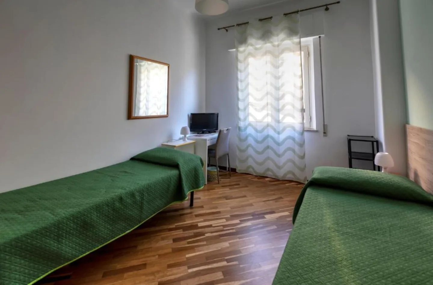 Camera doppia — due letti singoli con copriletto verde e tende ondulate